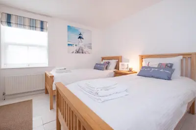 a bedroom with two beds and a window at Puddleduck Cottage in Aldeburgh