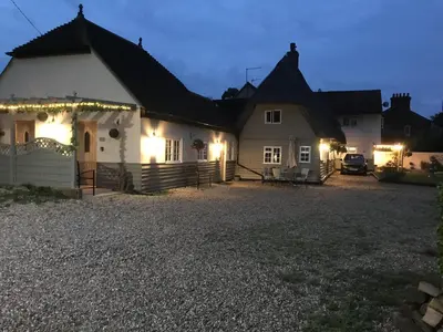 a house lit up at night with lights on it at Old Thatch Bambers Green in Takeley