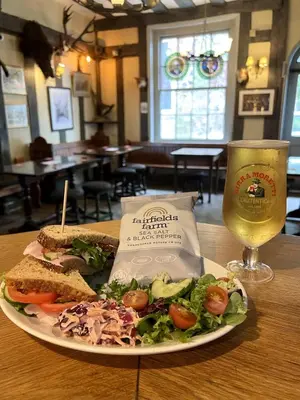 a plate of food with a sandwich and a glass of wine at The Blue Boar - Maldon in Maldon
