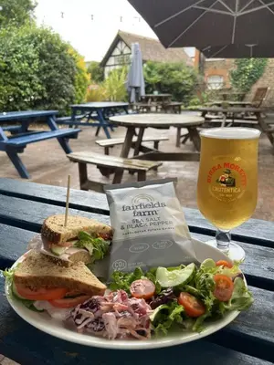 a plate with a sandwich and salad and a glass of beer at The Blue Boar - Maldon in Maldon