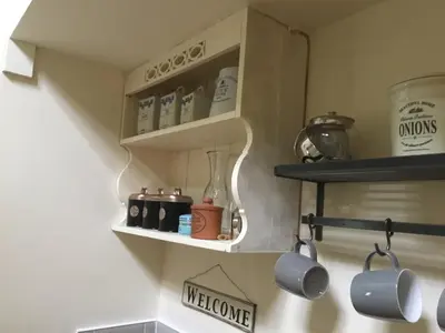 a kitchen shelf with mugs and cups on it at Ivy Todd cottage in Debden
