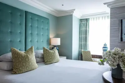 a bedroom with a large white bed with a green headboard at Roslin Beach Hotel in Southend-on-Sea