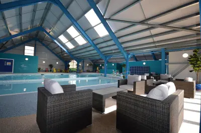 a pool with wicker chairs and a swimming pool at Camping Pods, Carlton Meres Holiday Park in Rendham