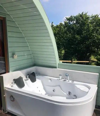 a white bath tub sitting in front of a window at Colemans Cottage Fishery in Wickham Bishops