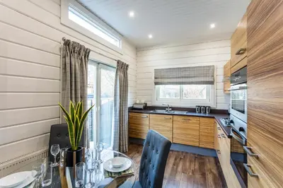 a kitchen with a dining table and a kitchen with wooden cabinets at Roydon Marina Village Lodges in Roydon