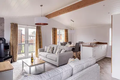 a living room with a couch and a kitchen at Roydon Marina Village Lodges in Roydon