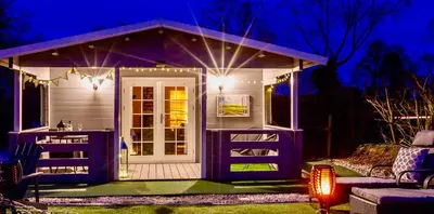 a small house with a porch at night at Sunset log cabin in Sudbury