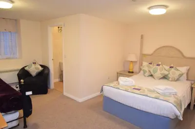 a bedroom with a bed and a black chair at Castle Lodge in Ely