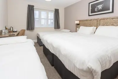 two beds in a hotel room with white sheets at The Aviator, formerly Smugglers Cove, Clacton On Sea by Marston's Inns in Clacton-on-Sea