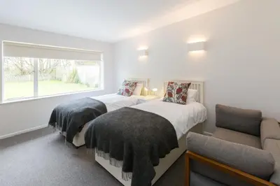 two beds in a room with a window and a chair at Invershin -Aldeburgh Coastal Cottages in Thorpeness
