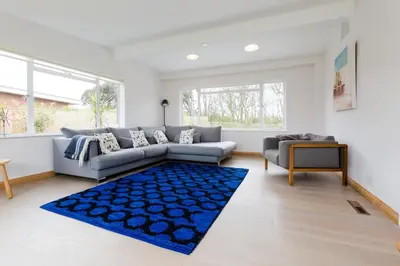a living room with a couch and a blue rug at Invershin -Aldeburgh Coastal Cottages in Thorpeness