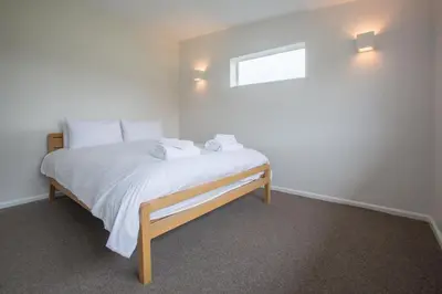a bedroom with a bed with white sheets and a window at Invershin -Aldeburgh Coastal Cottages in Thorpeness