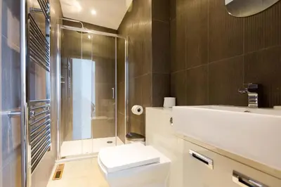 a bathroom with a shower and a toilet and a sink at Invershin -Aldeburgh Coastal Cottages in Thorpeness