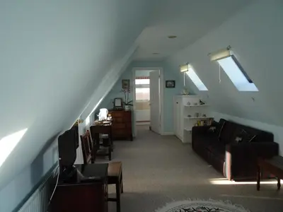 a living room with a couch and a staircase at The Newnham White House in Baldock