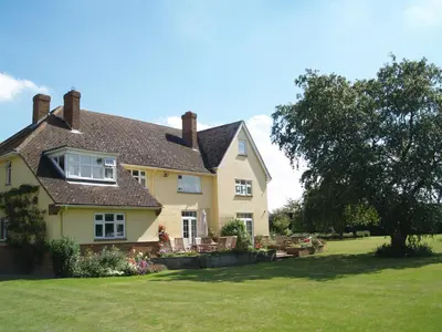 a yellow house with a yard with chairs and a tree at The Newnham White House in Baldock