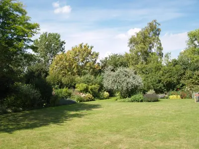 a garden with lush green grass and trees at The Newnham White House in Baldock