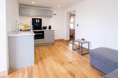 a kitchen and living room with a counter and a bed at Oak - Three Tuns Apartments, Pettistree, Wickham Market - by Aldeburgh Coastal Cottages in Pettistree