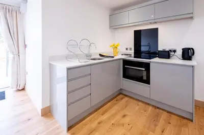 a kitchen with white cabinets and a counter top at Oak - Three Tuns Apartments, Pettistree, Wickham Market - by Aldeburgh Coastal Cottages in Pettistree