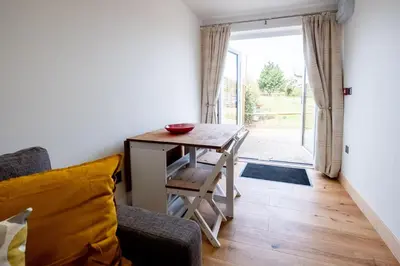 a living room with a table and a chair at Oak - Three Tuns Apartments, Pettistree, Wickham Market - by Aldeburgh Coastal Cottages in Pettistree