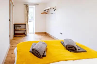 a bedroom with a yellow bed with towels on it at Maple - Three Tuns Apartments - Pettistree, Wickham Market - by Aldeburgh Coastal Cottages in Pettistree
