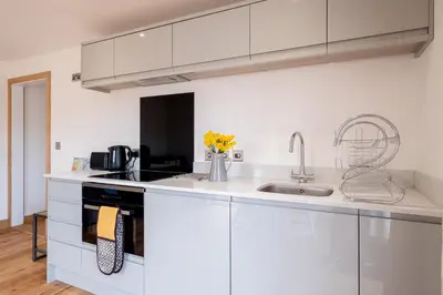 a white kitchen with white cabinets and a sink at Maple - Three Tuns Apartments - Pettistree, Wickham Market - by Aldeburgh Coastal Cottages in Pettistree
