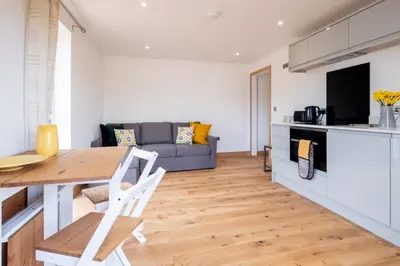 a kitchen and living room with a table and a couch at Maple - Three Tuns Apartments - Pettistree, Wickham Market - by Aldeburgh Coastal Cottages in Pettistree