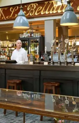 a man standing behind a bar in a restaurant at The Lion Inn in Chelmsford