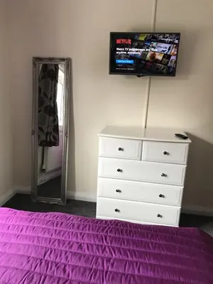 a bedroom with a bed and a dresser and a mirror at The Avenues in Chelmsford