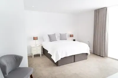 a white bedroom with a bed and a chair at Citystay Living - Park House in Cambridge