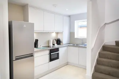 a kitchen with white cabinets and a stainless steel refrigerator at Citystay Living - Park House in Cambridge