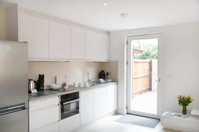 a kitchen with white cabinets and a sliding glass door at Citystay Living - Park House in Cambridge