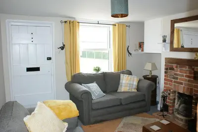 a living room with a couch and a fireplace at Wayside Cottage in Saint Osyth