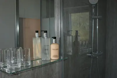 a glass shelf with bottles and glasses in a bathroom at Wayside Cottage in Saint Osyth