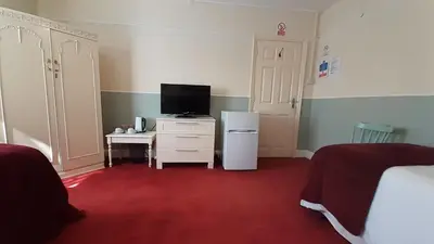 a bedroom with two beds and a tv and a desk at Kingsway Bed & Breakfast in Broxbourne