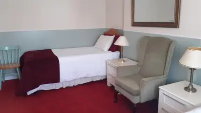 a bedroom with a bed and a chair at Kingsway Bed & Breakfast in Broxbourne