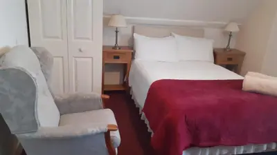 a hotel room with a bed and a chair at Kingsway Bed & Breakfast in Broxbourne