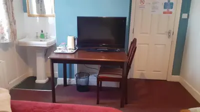 a desk with a television and a sink in a room at Kingsway Bed & Breakfast in Broxbourne