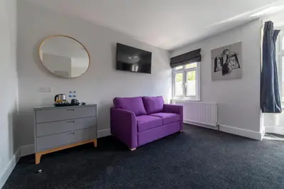 a purple couch in a room with a mirror and a dresser at The Norna in Cambridge