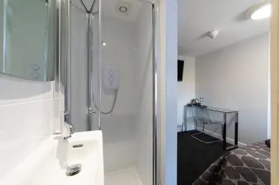 a white bathroom with a shower and a sink at The Norna in Cambridge