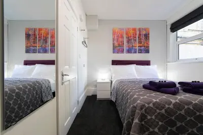 a bedroom with two beds and two windows at The Norna in Cambridge