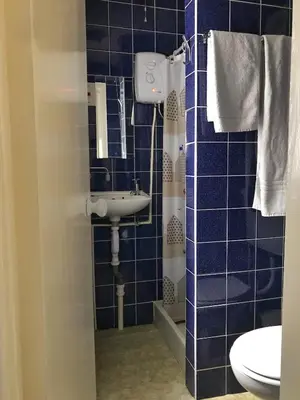 a blue tiled bathroom with a sink and a toilet at The Moorings B&B in Southend-on-Sea