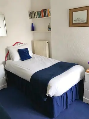 a bedroom with a large bed with a blue blanket at The Moorings B&B in Southend-on-Sea