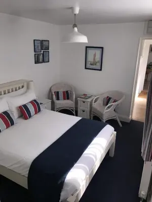 a bedroom with a bed with two chairs and a table at The Moorings B&B in Southend-on-Sea