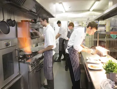 a group of men in a kitchen preparing food at The Oyster Smack in Burnham on Crouch