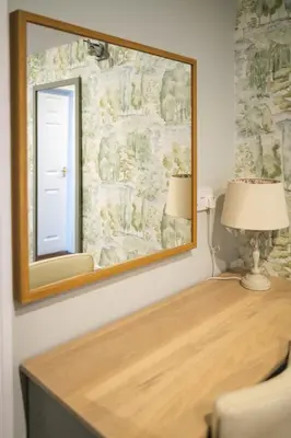a mirror on a wall next to a desk with a lamp at The Oyster Smack in Burnham on Crouch
