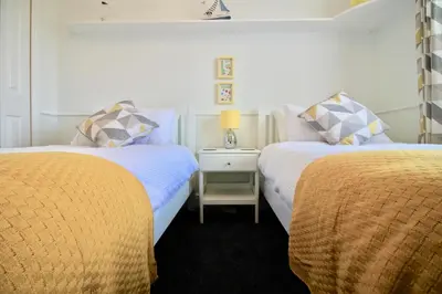 a bedroom with two beds and a table with a lamp at Seascape in Clacton-on-Sea