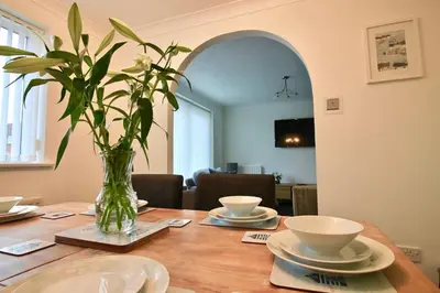 a dining room table with a vase of flowers on it at Seascape in Clacton-on-Sea