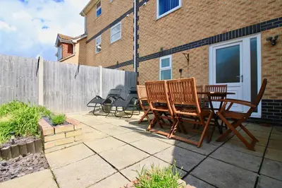 a patio with chairs and a table and a fence at Seascape in Clacton-on-Sea