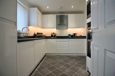 a kitchen with white cabinets and a tile floor at Seascape in Clacton-on-Sea