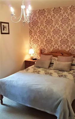 a bedroom with a large bed with a chandelier at The Pelican Guesthouse in Ashwellthorpe